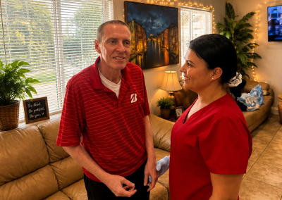 Male resident and female caregiver in red scrubs sharing a friendly conversation in the living room of Paradise Manor, a Florida ALF